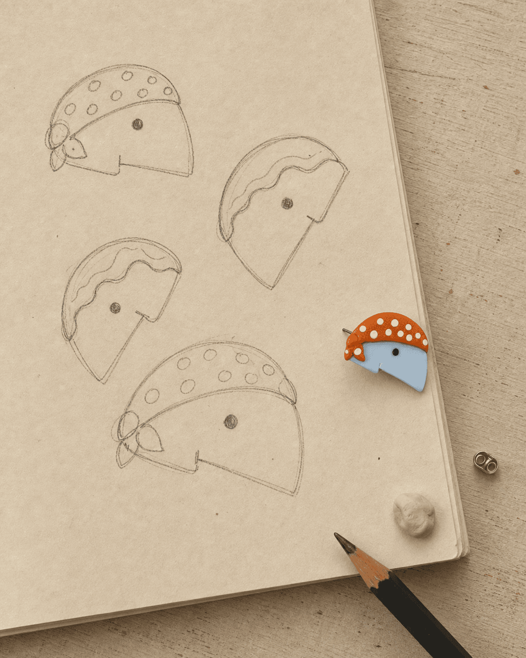 Graphite profile studies beside a finished mushroom character earring